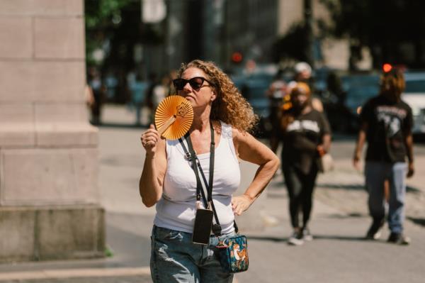 A woman in Manhattan holding a fan to cool off during a hot day