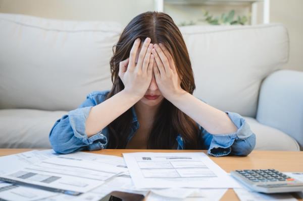 Young Asian woman covering her head with hands, stressed a<em></em>bout credit card debts and bills