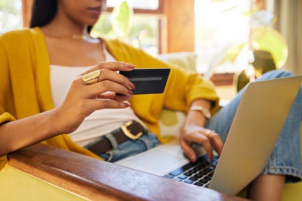 Closeup of a woman's hands using a credit card for o<em></em>nline shopping on a laptop at home