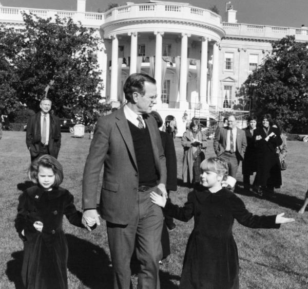 Former U.S. President George H. W. Bush walking hand in hand with granddaughters Barbara and Jenna on the south lawn of the White House in 1989.