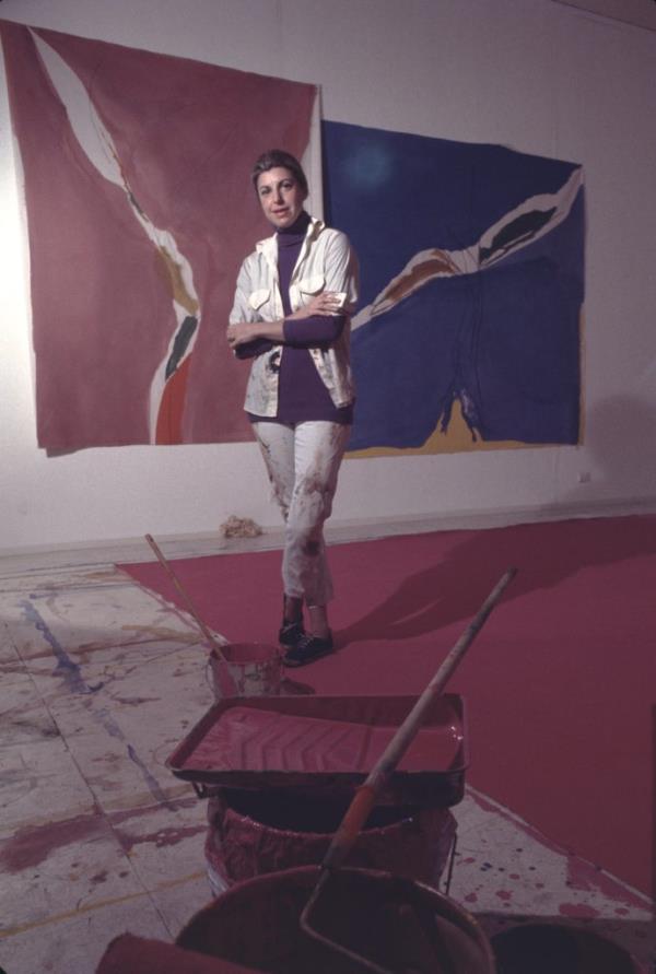 Helen Frankenthaler posing with two paintings