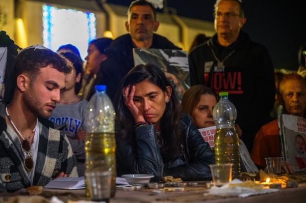 Shelly Shem Tov (C), the mother of Omer Shem Tov, reacts next to released hostage Itai Regev (L) and other relatives of hostages participate in a 'Kabalat Shabbat' (welcoming the shabbat) service at the Hostages Square outside the Tel Aviv Museum 