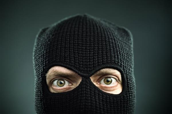 Closeup of a man's face covered in a black ski mask.