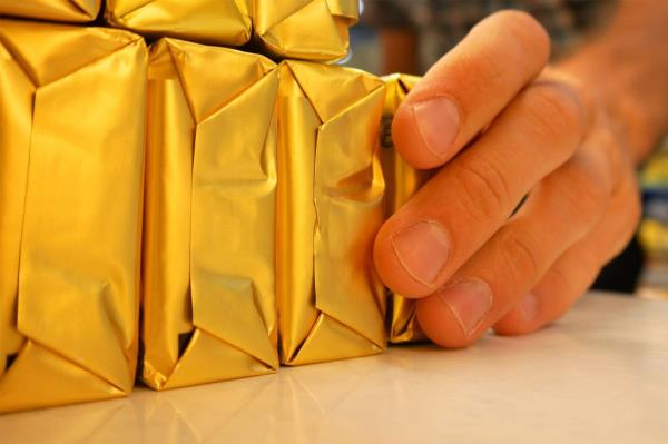 A man's hand holding several large packets of butter.