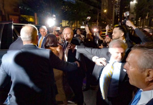 Prince Harry and Meghan Markle, escorted by security, walking through a crowd of photographers outside The Ziegfeld Theatre in New York City, May 2023