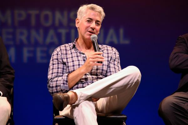 Bill Ackman sitting cross-legged with a microphone in his hand