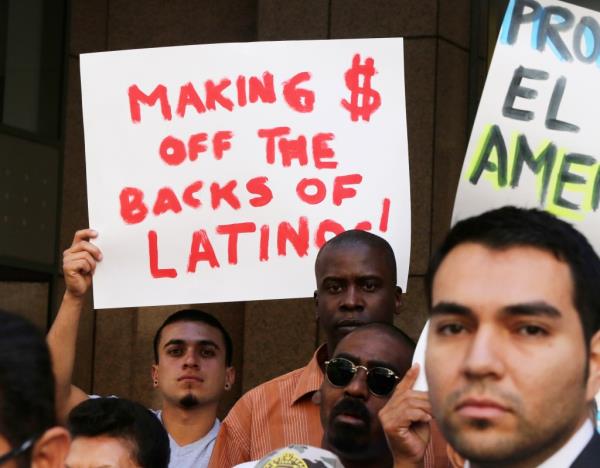 Protester with sign accusing Herbalife of making mo<em></em>ney off the backs of Latinos