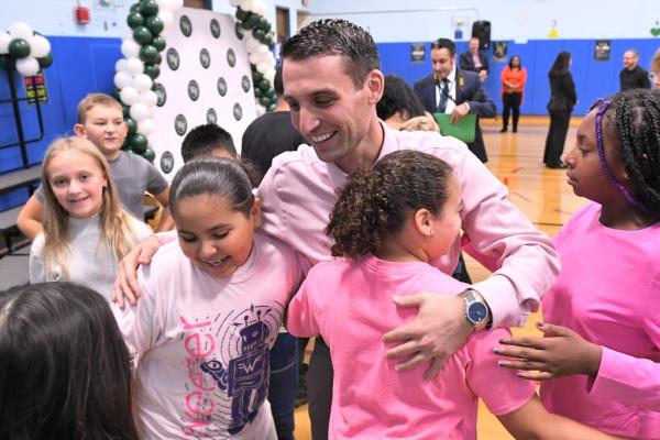 Outstanding educator John Melandro is hugged by a group of excited students, happy to celebrate his spectacular day.