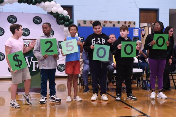 Kids displaying the $25,000 total Melandro won.