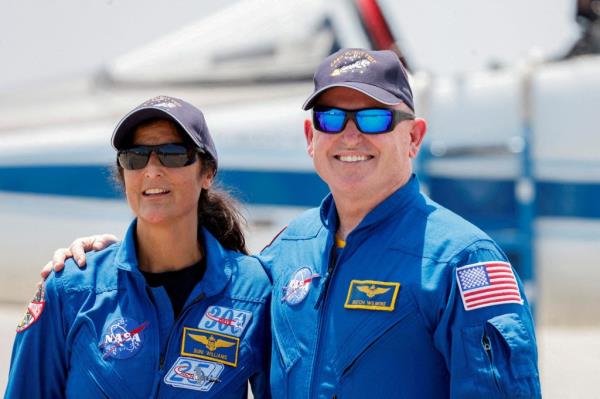 NASA astro<em></em>nauts Barry E. Wilmore and Sunita Williams in blue uniforms, posing in Cape Canaveral, Florida, prior to the launch of Boeing's Starliner-1 Crew Flight Test