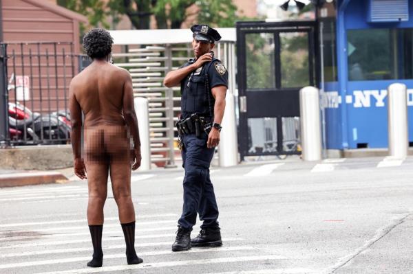 A naked man standing in front of a cop