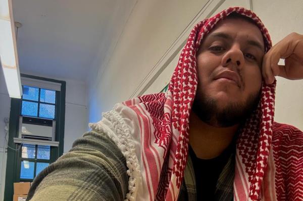 James Parra, paraprofessio<em></em>nal in Brooklyn, wearing Palestinian scarf over head, appearing to be in school building