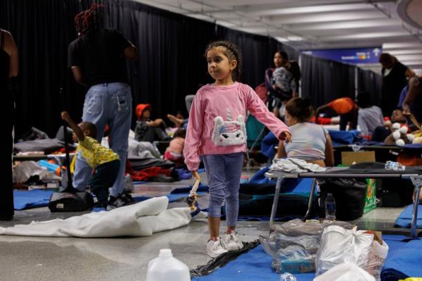 A young child plays with a doll while other recently arrived migrants sit on cots and the floor inside O'Hare Internatio<em></em>nal Airport on Aug. 31.