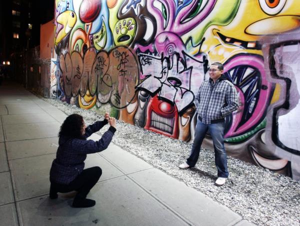 People pose in front of the Bowery wall.