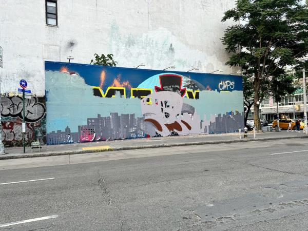 A fires burns in front of David Flores’s flowery, red mural of a motorcycle  on the Bowery wall. 