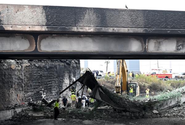 Workers inspect and clear debris from a section of the bridge that collapsed on Interstate 95 after an oil tanker explosion on June 12, 2023 in Philadelphia, Pennsylvania.  