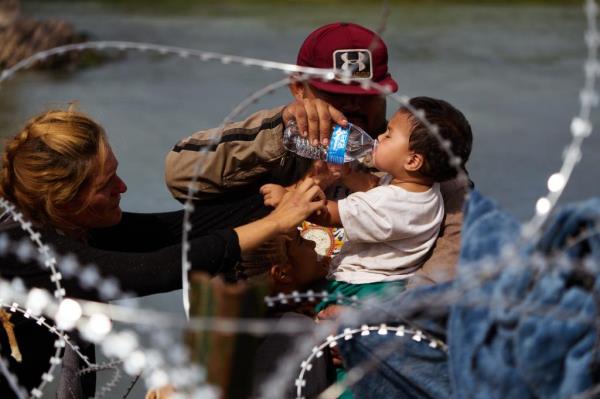 Migrants moving along the razor wire fencing placed along the US-Mexico border. 