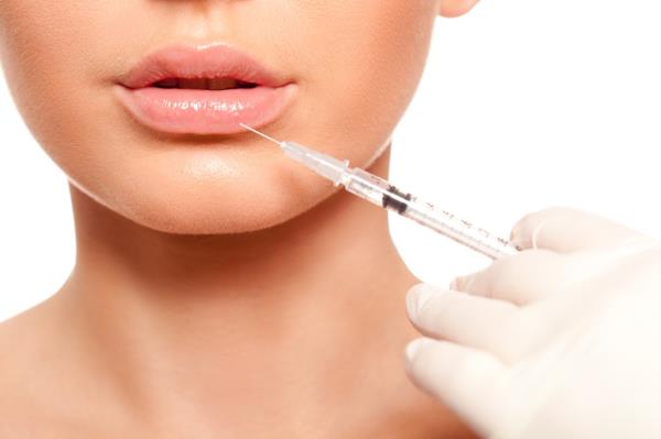 Closeup of a woman's face with a needle next to the lips.