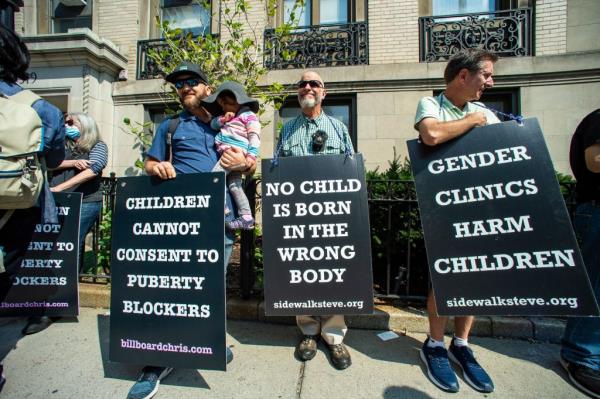 A group of people, including Simon Evans, holding protest signs outside Boston Children's Hospital, demo<em></em>nstrating against gender affirmation treatments and surgeries on minors.