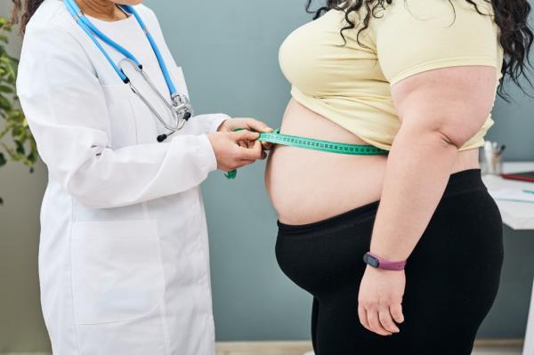 A nutritio<em></em>nist measuring a woman's waist with a tape to assess obesity and prescribe a weight loss diet