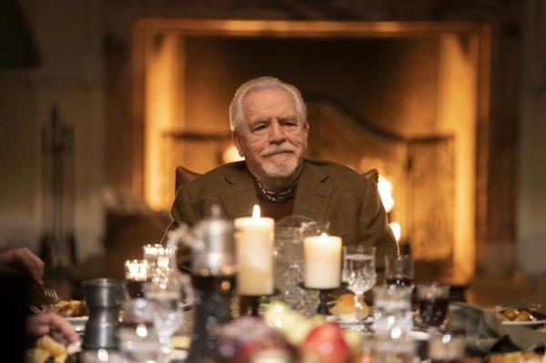 Brian Cox sitting at a table. 