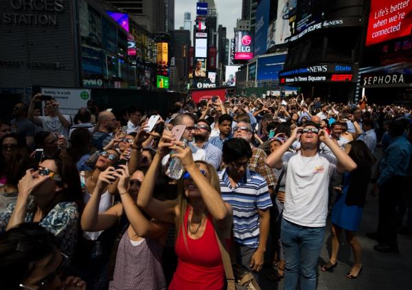 A crowd reacts to the view of a partial solar eclipse