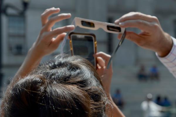 People taking a photo of the eclipse through solar eclipse lenses 