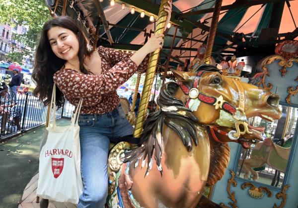 Malena Galletto poses with Harvard University canvas tote bag on top of the carousel at Bryant Park