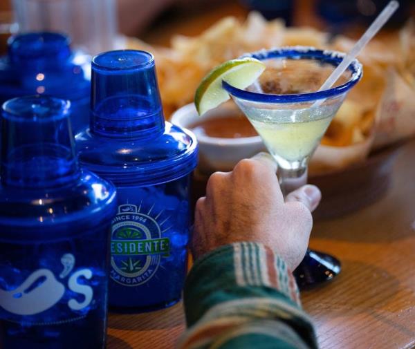 A hand holding a Presidente Margarita with a lime wedge served at Chili's restaurant