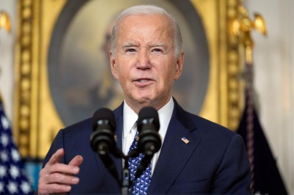 Joe Biden speaking in the Diplomatic Reception Room of the White House, with micropho<em></em>nes in front of him.