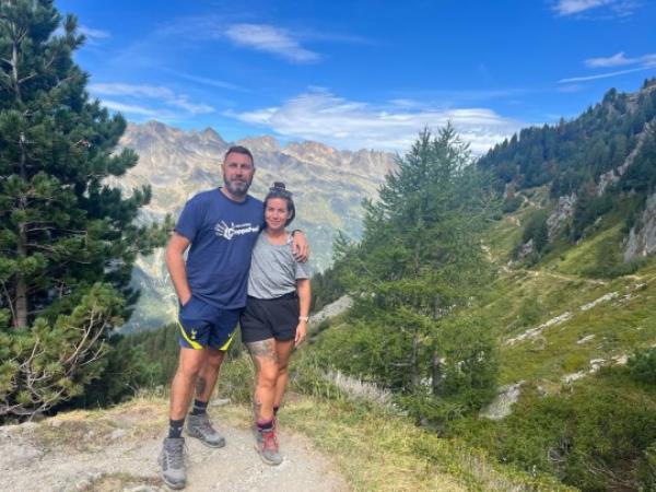 Danni Moore on a hike surrounded by trees and stood next to a tall male