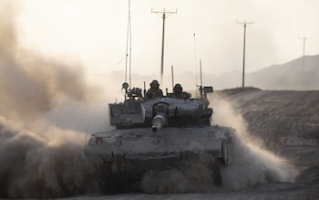 Israeli soldiers in a tank as it drives along the border with the Gaza Strip