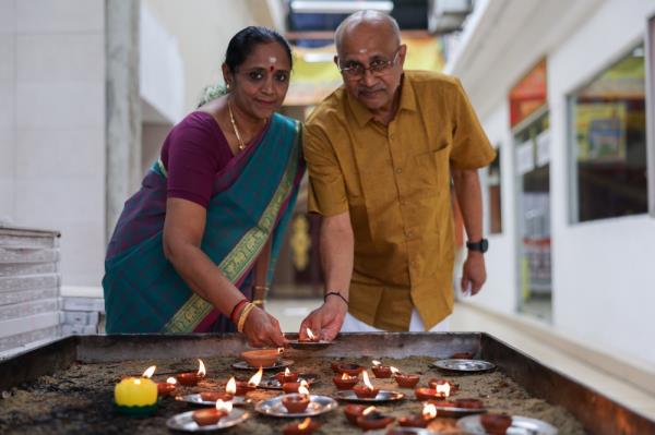 Narayanan, 66, (right) and his wife Indar, 62, light a vilakku or tradition lamp while performing prayers in co<em></em>njunction with Deepavali at the Arulmigu Rajamariamman Devasthanam Temple in Johor Baru November 12, 2023. — Bernama pic