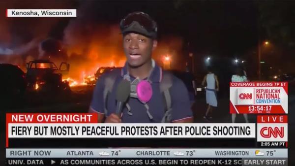 A reporter from CNN stands in front of a fire in Kenosha with the chyron reading, 