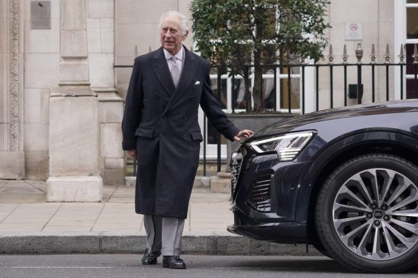 King Charles III walking next to a car on the street in London.