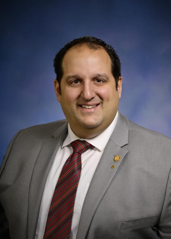 Rep. Joseph Aragona in a suit and tie proposing legislation to reward reporters for uncovering wasteful government spending