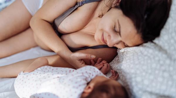 mother cuddles with baby in bed