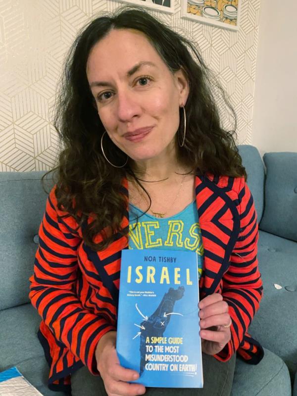 Shira Goldman poses with Israel book in her home.