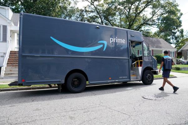 Amazon delivery driver walks back to truck on residential street.