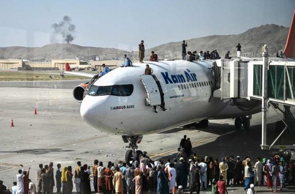 Afghan people climbing on top of a plane as they wait to be evacuated at the Kabul airport.