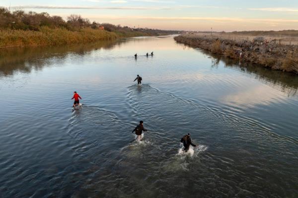 In an aerial view, immigrants wade across the Rio Grande while crossing from Mexico into the United States on January 07, 2024