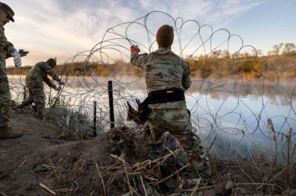 Texas Natio<em></em>nal Guard soldiers install additio<em></em>nal razor wire lie along the Rio Grande