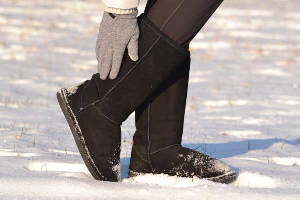 Person posing in black UGG boots in snow.