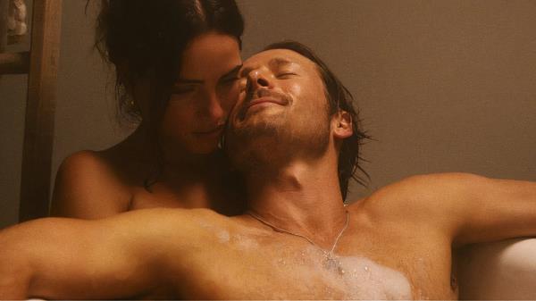 Glen Powell and Adria Arjona in Netflix's Hit Man sitting in the bathtub together