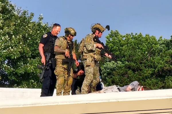 Police officers in uniform standing over the body of shooter Thomas Matthew Crooks at a campaign rally in Butler, PA