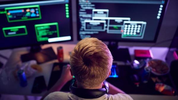 Male Teenage Hacker Sitting In Front Of Computer Screens Bypassing Cyber Security