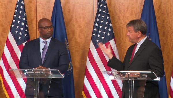 Rep. Jamaal Bowman and challenger George Latimer debating at podiums with flags in the background