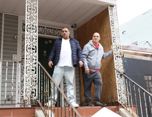 Two men standing on the porch of a house at 3259 Hull Avenue in the Bronx, New York