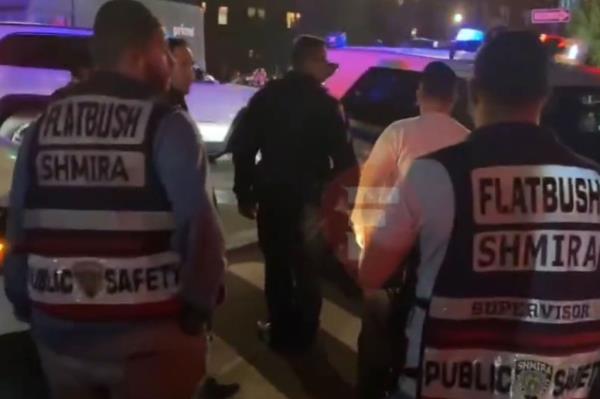 Police surround a cop car with its doors open.