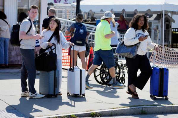 Travelers wait for ride shares after disembarking the ferry from Nantucket Island,